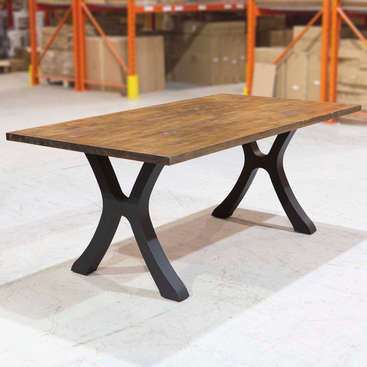 Wooden table with black metal legs in a warehouse setting