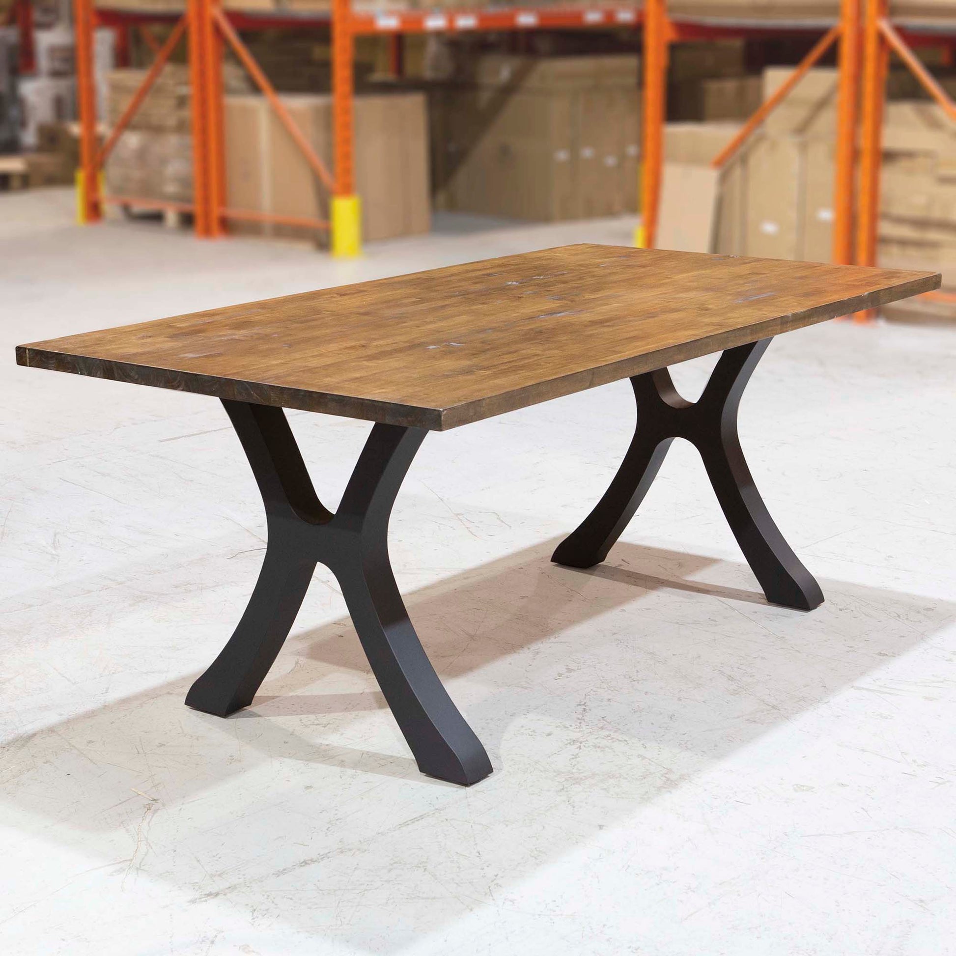 Wooden table with black metal legs in a warehouse setting